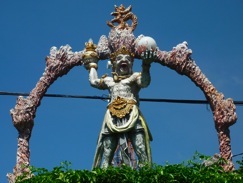 A carved statue under a decorated arch against a blue sky