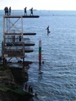 People diving into the sea from a tall diving platform